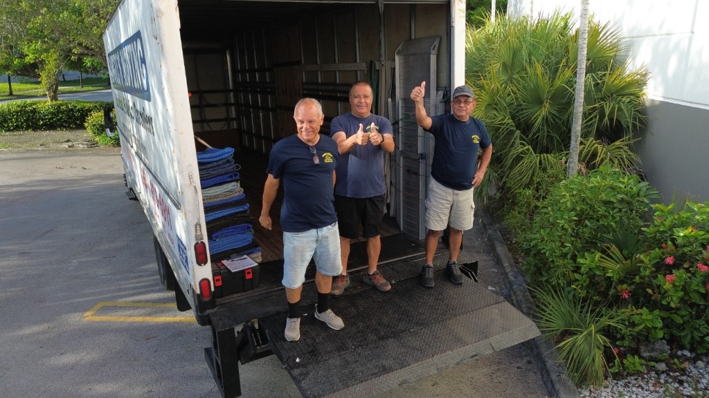 Angel's Moving crew smiling and giving thumbs up at truck ramp